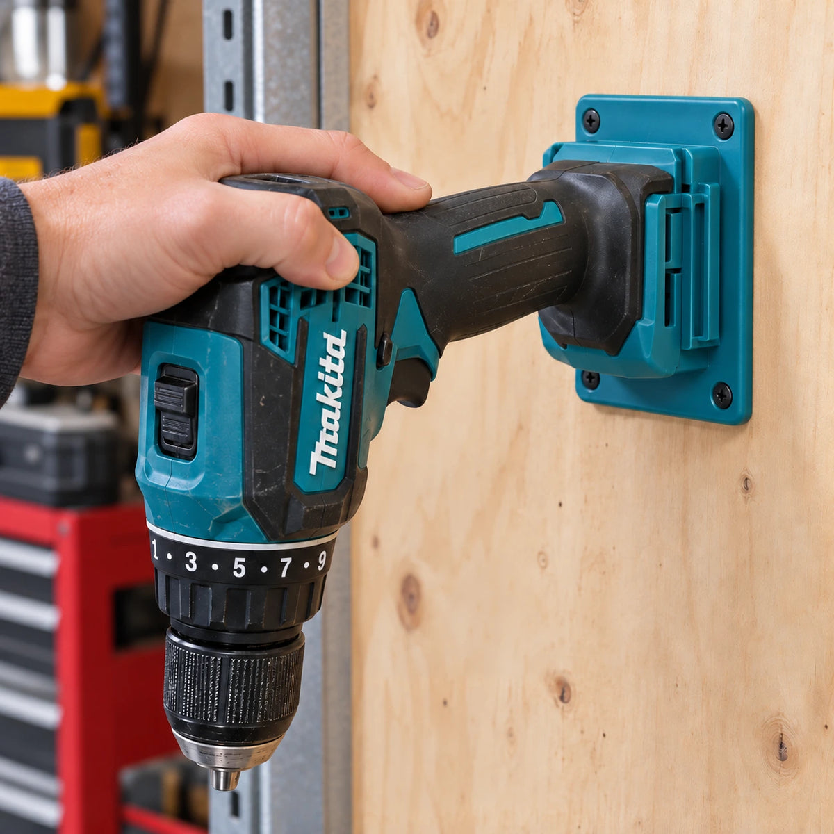 En hånd skyver en Makita-drill inn i en turkis holder via batterifestet